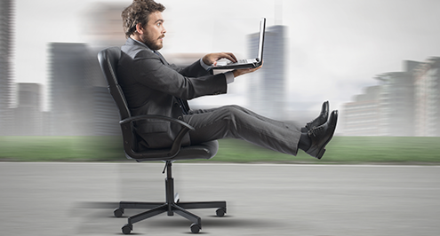Businessman in office chair racing down a racetrack business growth